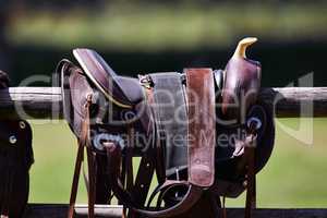 Ready to ride. Cropped shot of a saddle on a fence.