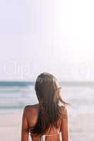 The beach will always be the perfect summer destination. Rearview shot of an unrecognizable young woman at the beach.