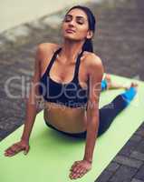 Ill bend but I wont break. Shot of a beautiful young woman practising yoga outdoors.