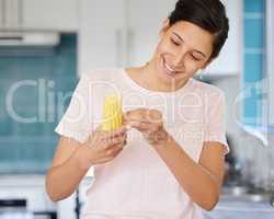 Make sure you remove those fibers. Shot of a young woman preparing corn to be cooked.