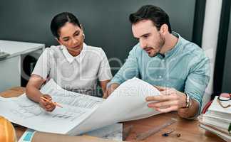 Theyre the pros. Shot of two architects working with blueprints in an office.