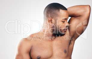 When you smell good, you feel good. Studio shot of a handsome young man smelling his armpit against a white background.