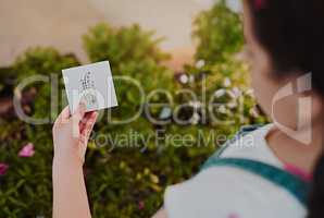 I need to identify this one. Cropped shot of an unrecognizable young girl holding a placard with a plant drawing on it while analysing plants at home.