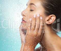 You are rare, luminous, and valuable. Shot of a young woman taking a shower against a blue background.