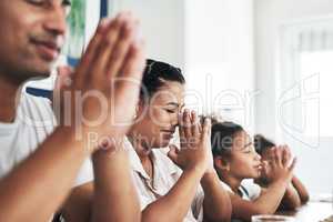 Prayer brings us together as a family. Shot of a family praying together at home.