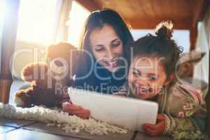 Fascinated by all thats online. Shot of a mother and her little daughter using a digital tablet together at home.