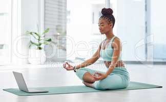 Learning the importance of yoga online. Full length shot of an attractive young woman sitting with her legs crossed and following an online yoga class.
