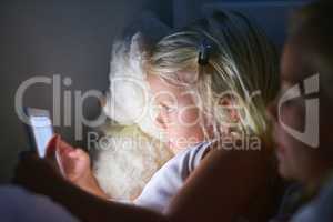 Bedtime has become a lot more interactive. Shot of two little girls using a digital tablet before bedtime.