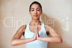 Completely calm and relaxed.... Shot of a young woman doing yoga indoors.