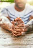 True to his religion. Cropped shot of a young man holding his rosary while praying.