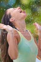 Summer showers to awaken the senses. Cropped shot of a young woman standing happily in the rain tasting the raindrops.