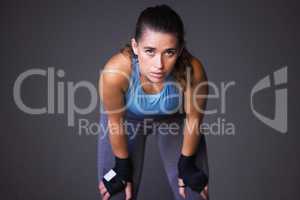 Stay strong mentally and physically. Portrait of a sporty young woman catching her breath against a grey background.