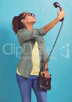 Lets do this the old-fashioned way. Shot of a young woman talking a selfie on an old fashioned telephone.