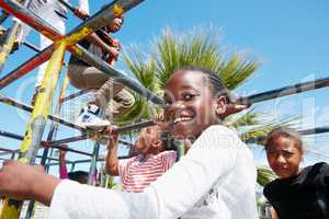 The world is their playground. Portrait of a happy little girl playing on a jungle gym.