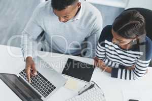 Sticking to this method will surely guarantee us success. High angle shot of two young businesspeople going through figures on a laptop at their office desk.