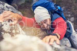 What doesnt kill you makes you stronger. Shot of a happy hiker climbing over rocks on a mountain trail.