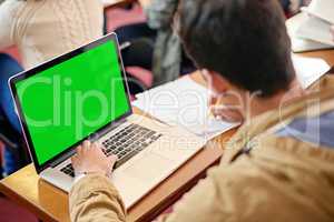 Using tech to further his education. Overhead shot of a student using his laptop at his desk in class.