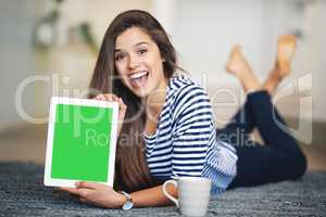 This is a site youre going to want to visit. Portrait of an ecstatic young woman lying on the floor at home holding up a digital tablet with a chroma key screen.