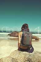 You may be poor on money, but rich on life. Shot of a young backpacker admiring the beautiful scenery at the beach.