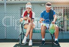 Time to relax for a bit. Full length shot of two young tennis players sitting down and having a conversation together outdoors on the court.
