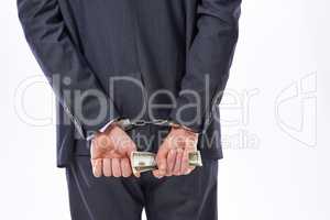 Fail with honor instead of succeeding with fraud. Rear view studio shot of a businessman in handcuffs holding American Dollars.