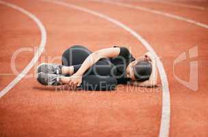 Someone bring me an ice pack. Shot of an athletic young woman suffering from a sports injury while out on the track.