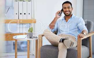 Sitting down to receive even more good news. Shot of a young businessman talking on a cellphone in an office.