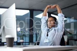 Some calls just make you question your choice in career. Shot of a young man stretching while using a headset and computer in a modern office.