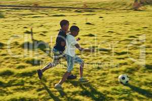 Football fun with a friend. Shot of a two children playing soccer together in a field outside.