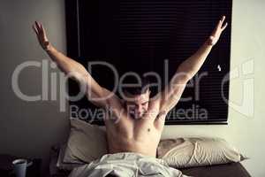 Today is going to be awesome. Shot of a handsome young man stretching after waking up rested in bed.