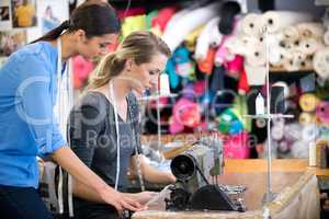 Everything has to be perfect. Two women working on a garment at a workbench inside their fabric shop.