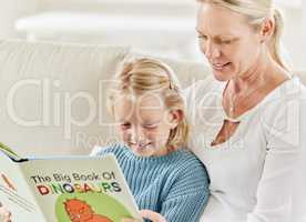Slow and steady wins the race. Shot of a young mother and daughter reading on the sofa at home.