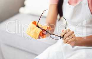 Theyre no good if theyre not clean. Cropped shot of a woman cleaning her glasses while sitting at home.