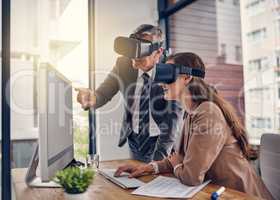 Transferring their ideas through new dimensions. Shot of two businesspeople wearing VR headsets while working on a computer in an office.