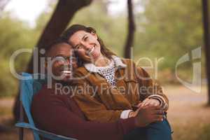 Nothing says I love you like your undivided attention. Shot of a woman sitting on her boyfriends lap while out camping in the wilderness.