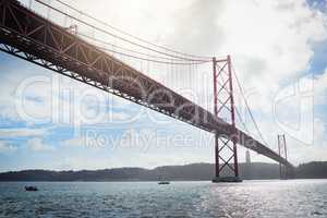 From one place to another. Low angle shot of a massive bridge over the ocean with clouds in the background outside during the day.