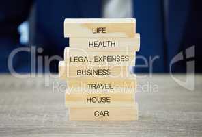 The more youre covered, the better youll feel. Shot of an unrecognisable businessman assembling wooden blocks with insurance related words on them.