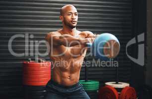 Generating power and strength with every swing. Shot of a muscular young man exercising with a kettlebell in a gym.