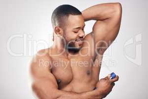 Clean is the way to go. Studio shot of a handsome young man spraying deodorant on his armpit against a white background.