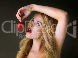 Lust at first bite. Studio shot of a gorgeous young woman eating a red apple suggestively against a dark background.