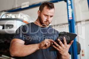 Open the app to find a reliable and trustworthy mechanic near you. Shot of a mechanic using a digital tablet while working in an auto repair shop.
