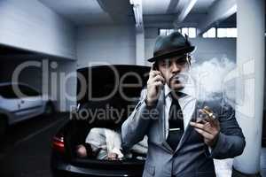Letting his employers know the job is done. An arrogant mobster smoking a cigar and informing his employer that the abduction was successful.