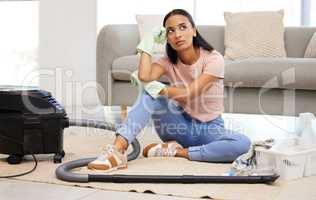 Do I have to do all this cleaning. Shot of a young woman sitting on the floor looking contemplative at home.