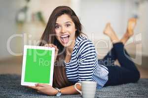Can you believe this site. Portrait of an ecstatic young woman lying on the floor at home holding up a digital tablet with a chroma key screen.