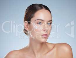 For skin that looks effortlessly smooth. Studio portrait of an attractive young woman moisturizing her face against a grey background.