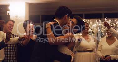 Love was meant to be synonymous with happiness. Cropped shot of an affectionate young newlywed couple dancing while their guests are holding up sparklers at their wedding reception.