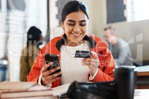 I should spoil myself for studying so hard. Shot of a young female student using a phone and credit card at college.