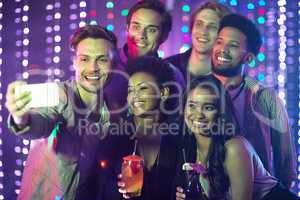 Everybody say cheese. Shot of a happy group of friends taking a selfie with a smartphone in a nightclub.