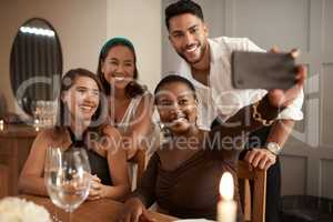 Say champagne. Shot of a young group of friends using a cellphone to take selfies during a New Years dinner party.