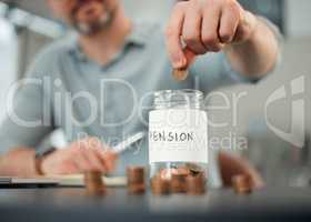 Its important to save. Cropped shot of an unrecognizable man putting coins into a jar marked PENSION while working on his finances at a desk at home.